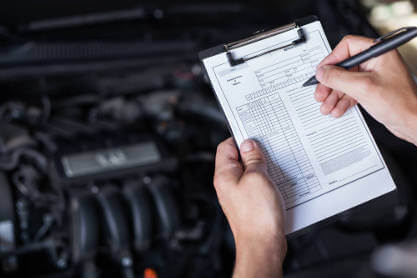 mechanic-holding-motor-service-form-while-looking-at-engine