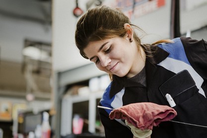 Young female mechanic wiping the engine oil dipstick